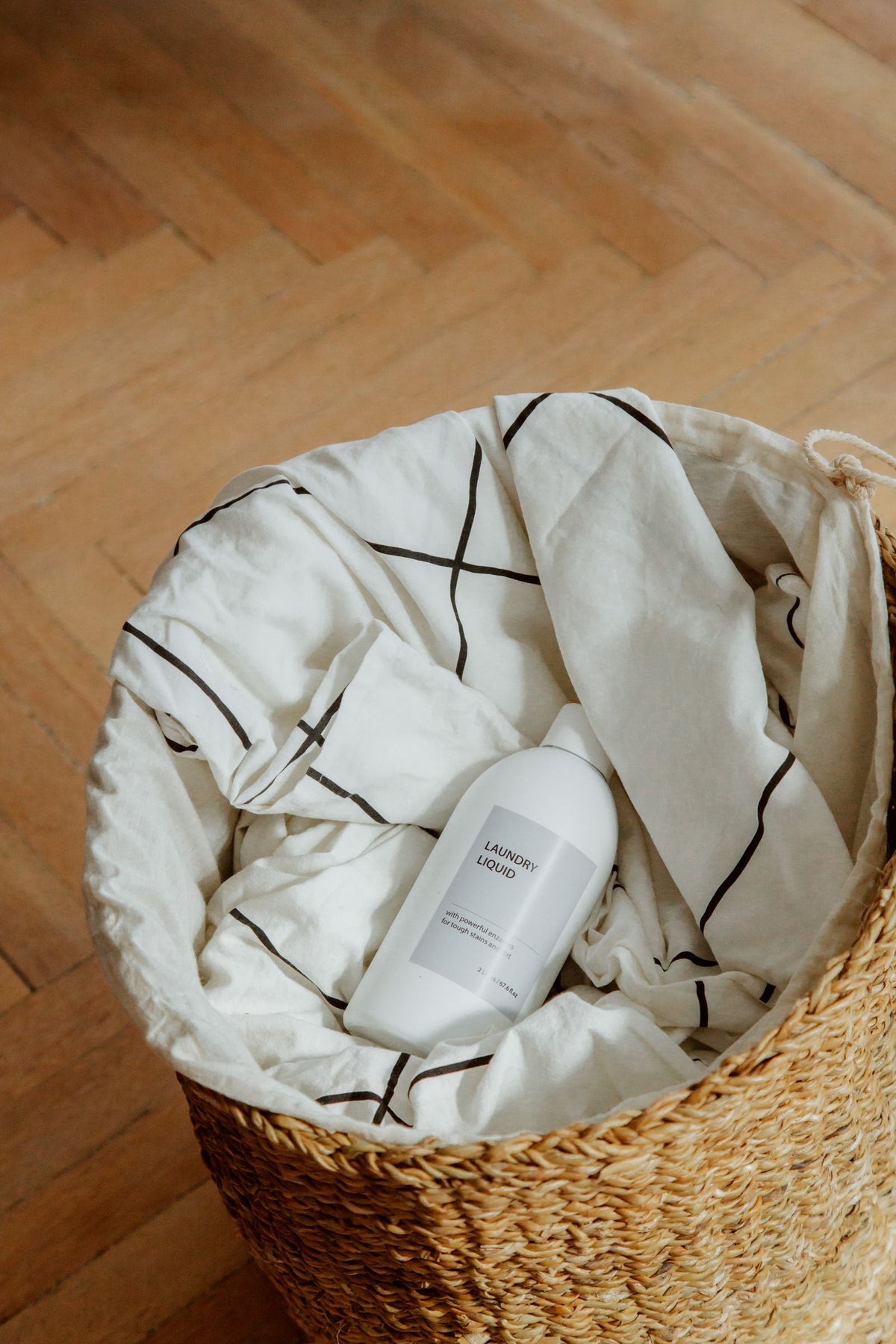 Laundry detergent and folded linen fabric in a woven basket - how to wash linen without shrinking it