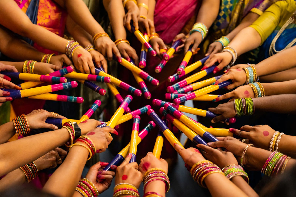 People with dandiya sticks celebrating Navratri garba night in colourful festive outfits, India